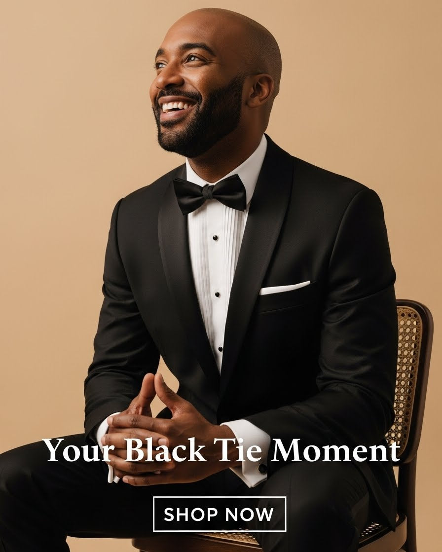 Man in a black tuxedo sitting on a chair with 'Your Black Tie Moment' text and 'Shop Now' button.